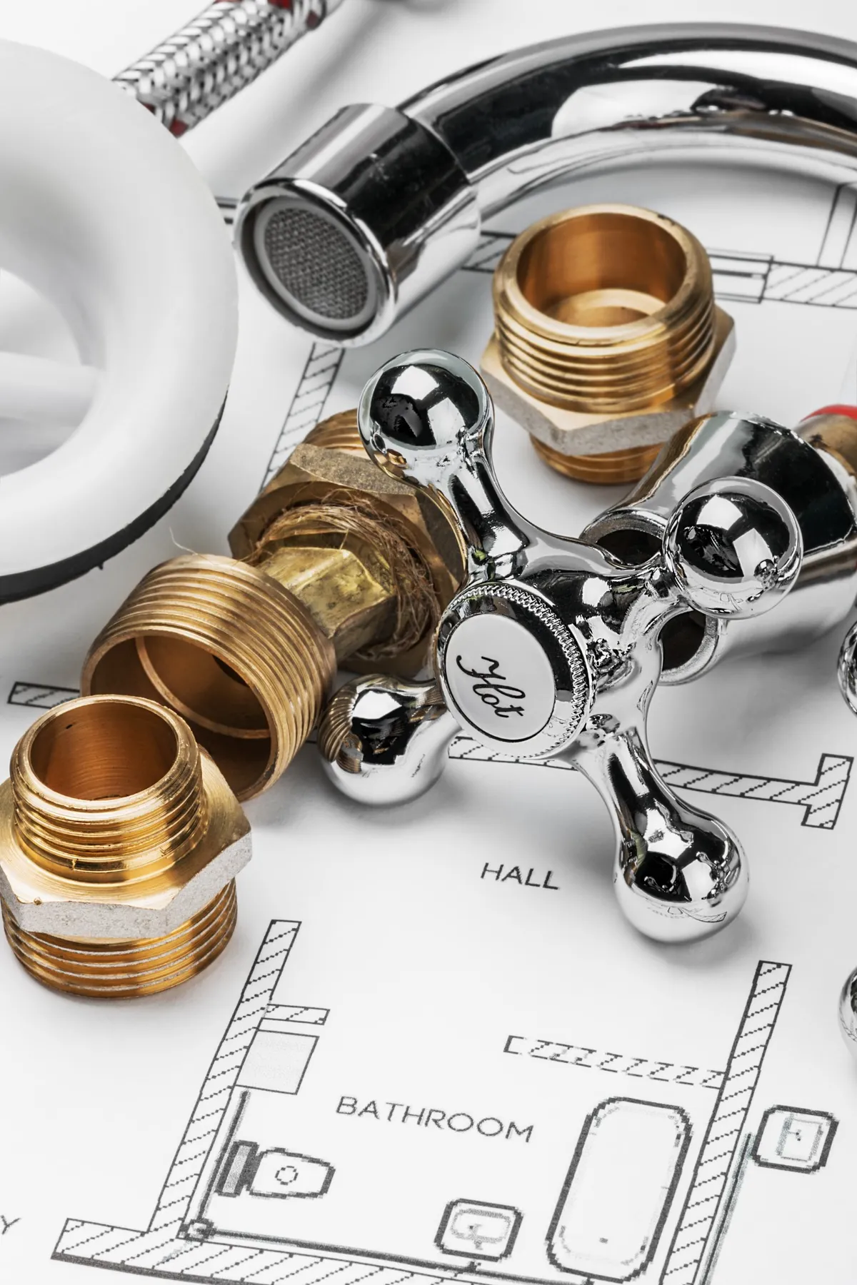 Pièces de robinetterie et raccords sur un plan d'installation, utilisés par une entreprise de plomberie pour des travaux de salle de bain ou cuisine.